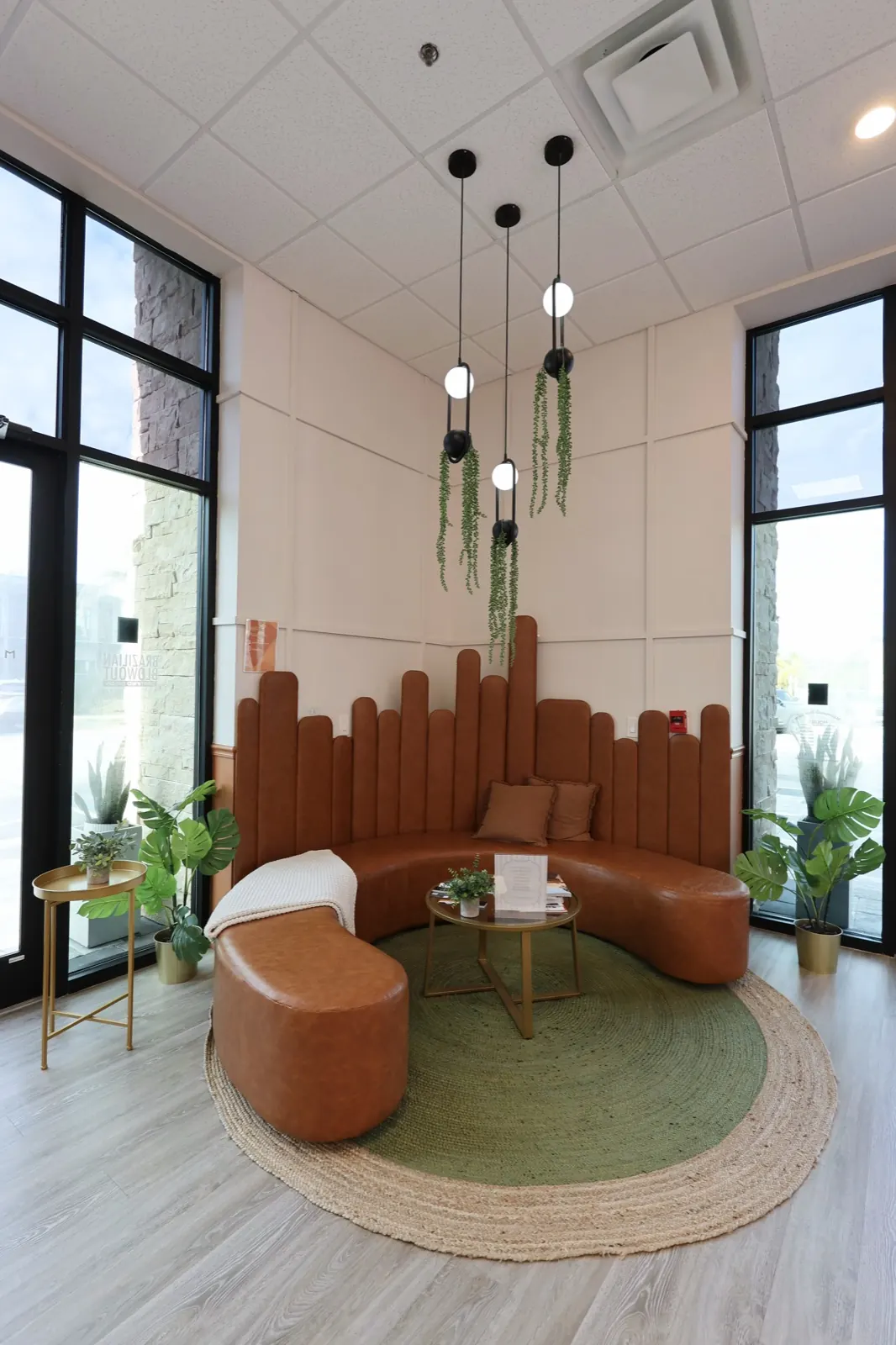 Salon lounge with a curved caramel sofa and green rug